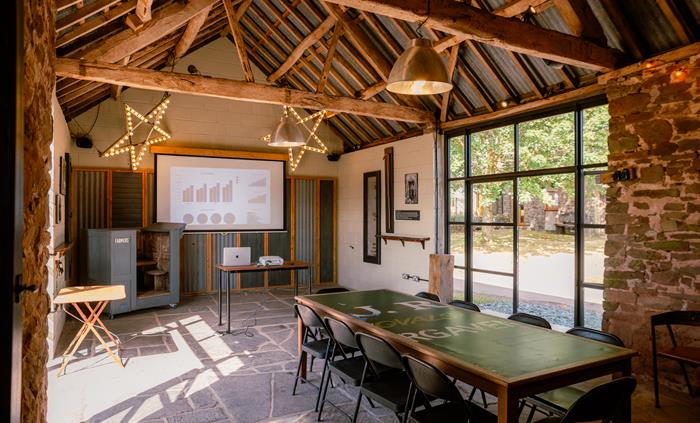 Interior of stone barn with large table set up and presentation on projector screen